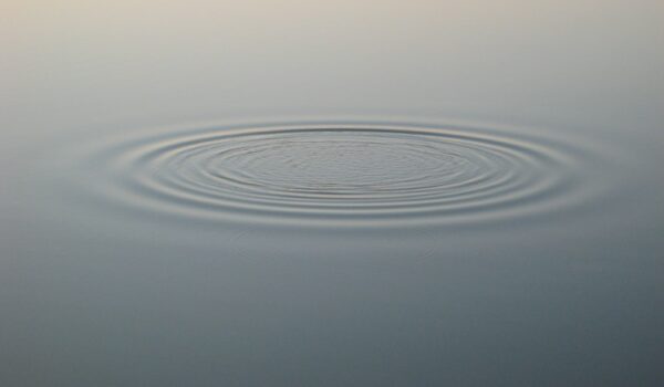 a ripple in a body of water with a brown sky in the background